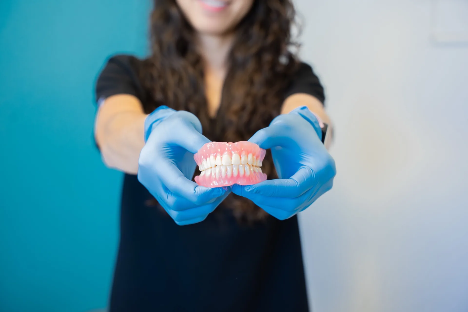 Oasis Dental team member holding a partial denture