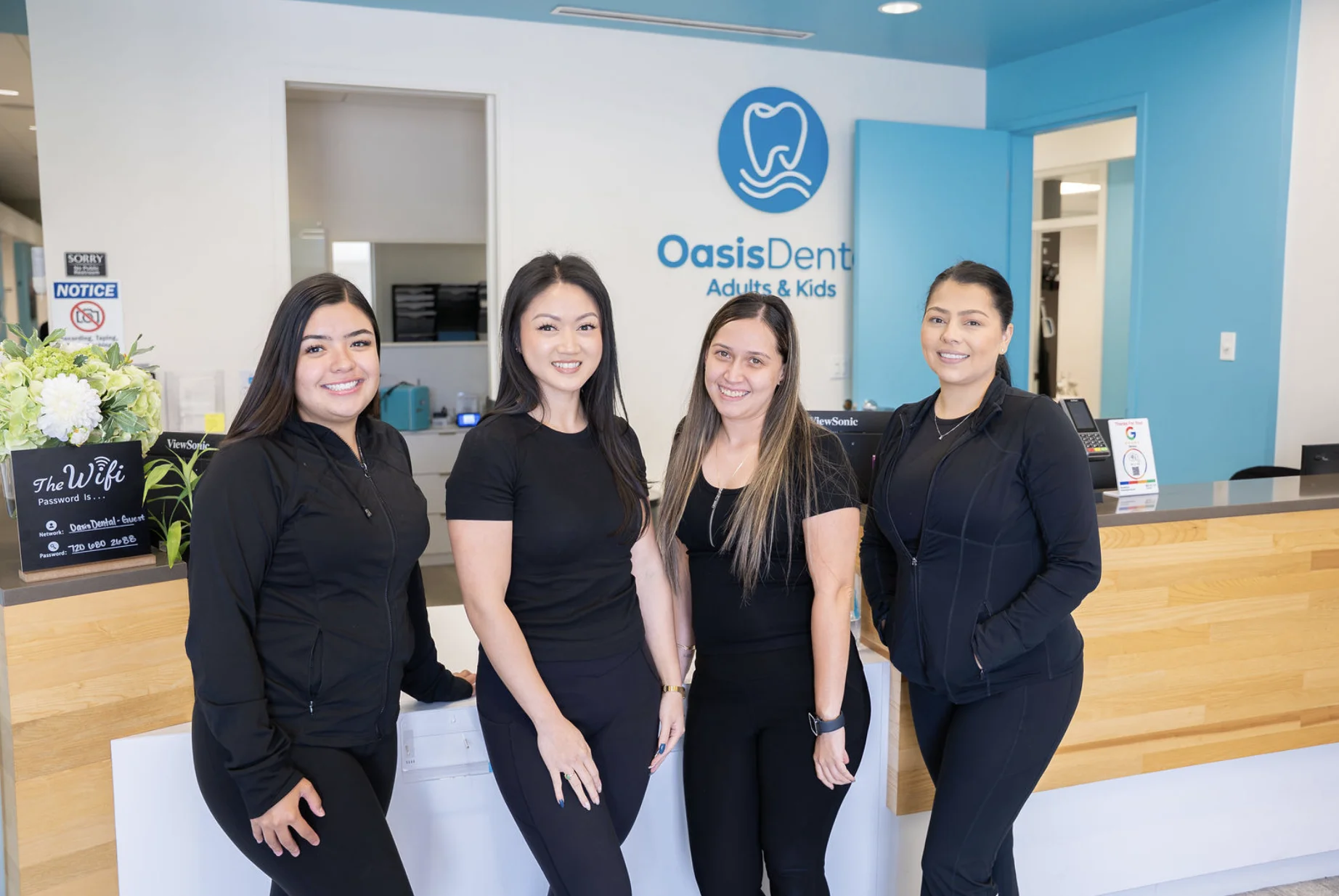 Oasis Dental front desk team smiling at the reception counter