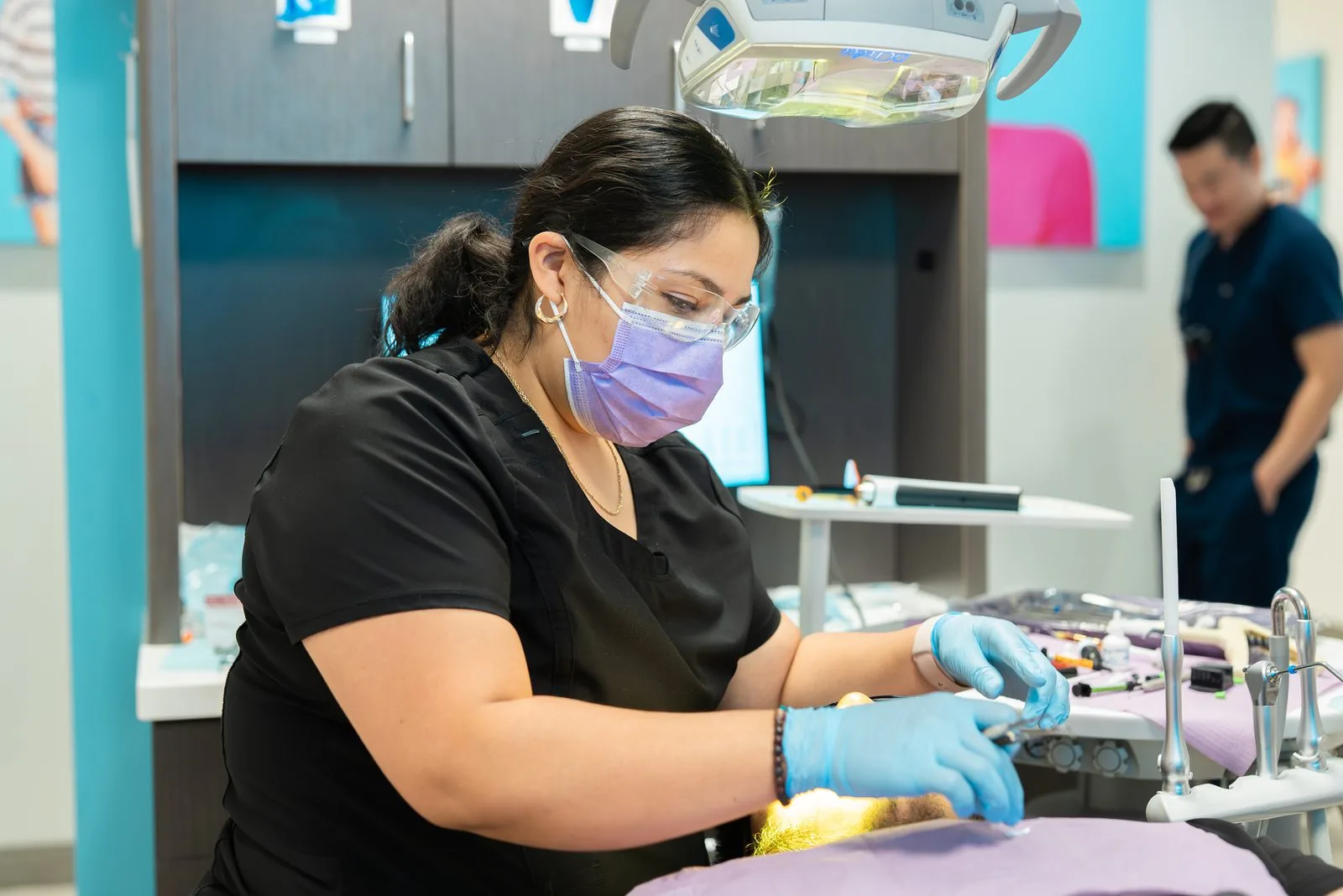 Oasis Dental hygienist in a mask and safety glasses cleaning a patient's teeth