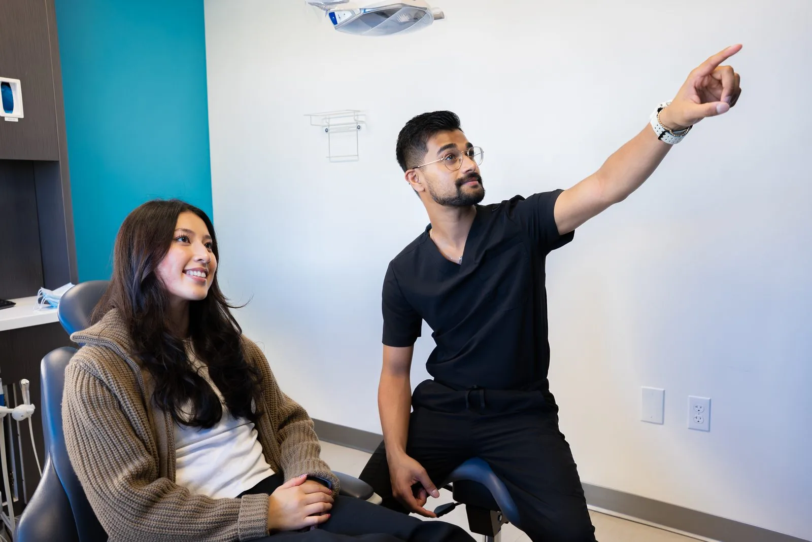 A dentist explaining treatment options to a smiling patient at Oasis Dental
